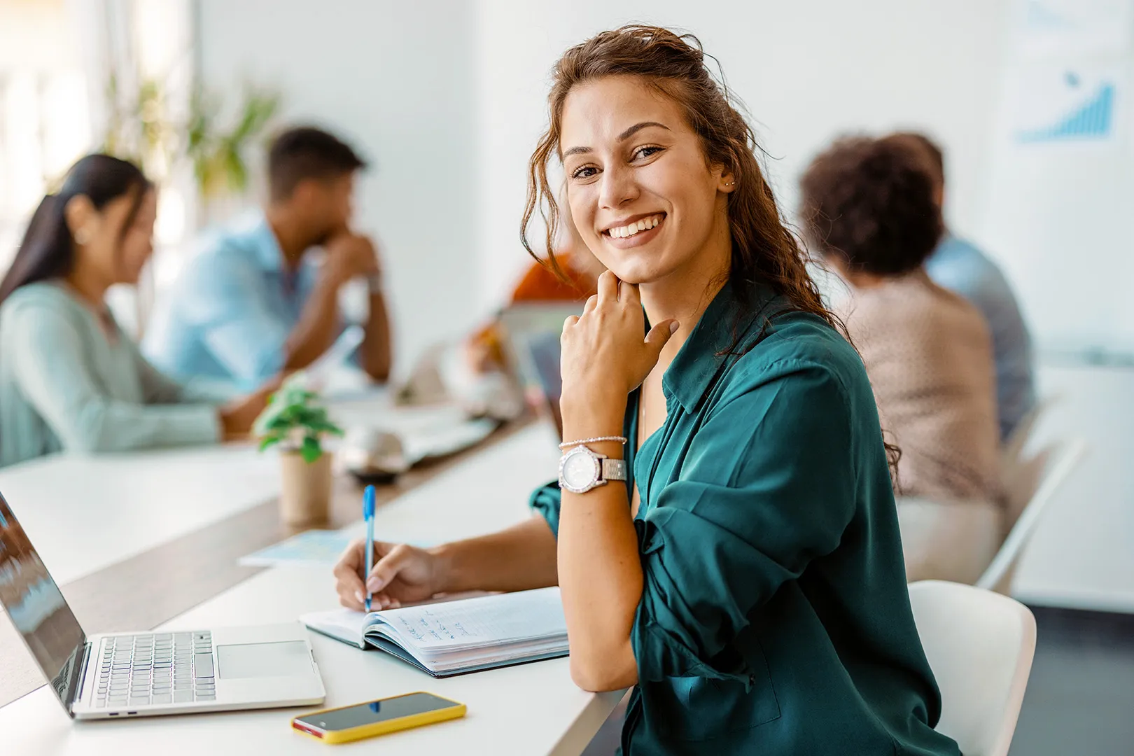 A woman smiling while writing in a notebook