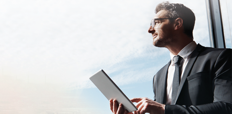 Man looking out window while on tablet