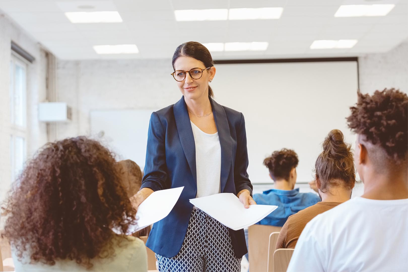 Professor handing students pieces of paper in a classroom
