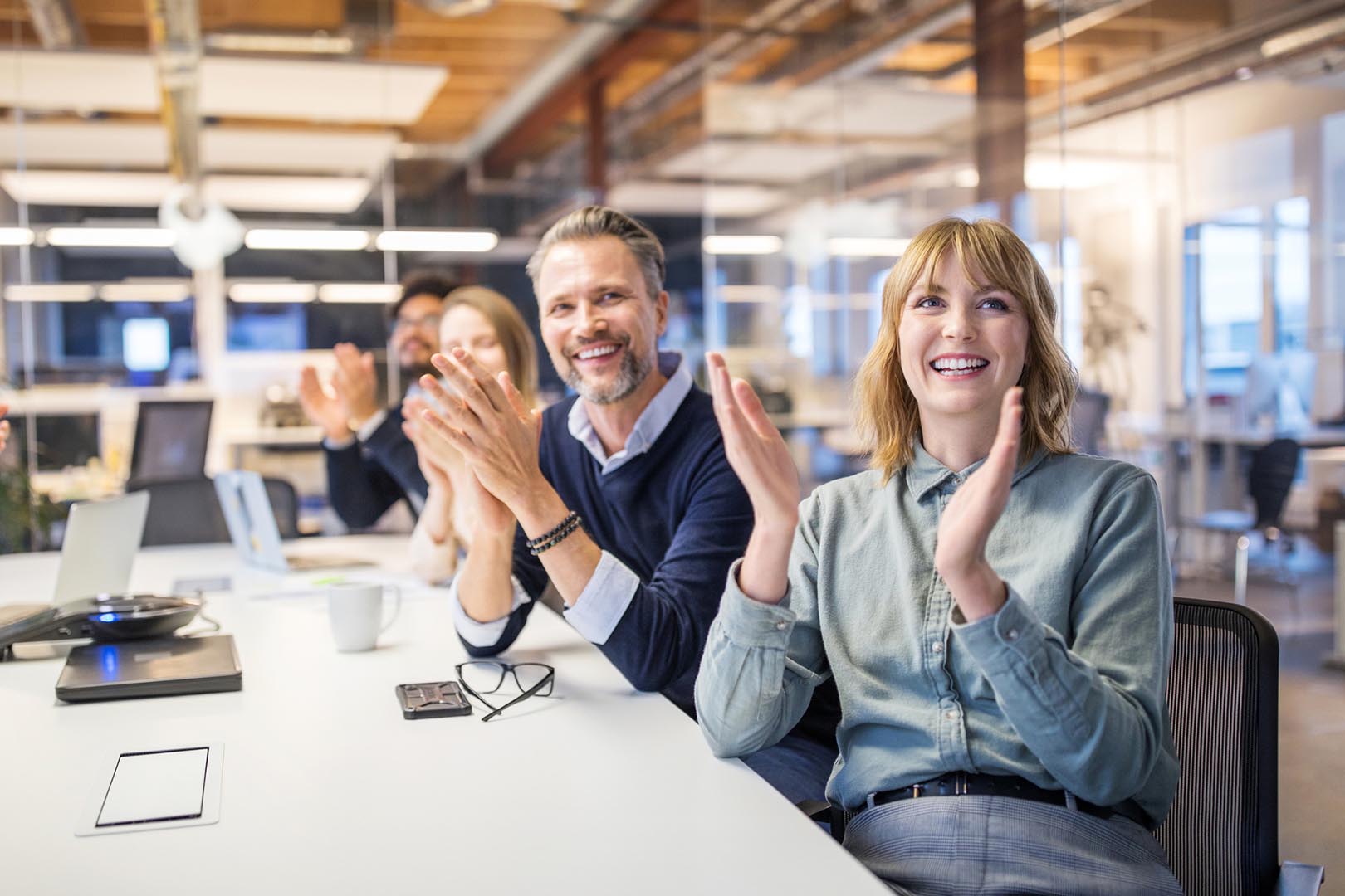 Staff at table clapping in a conference room