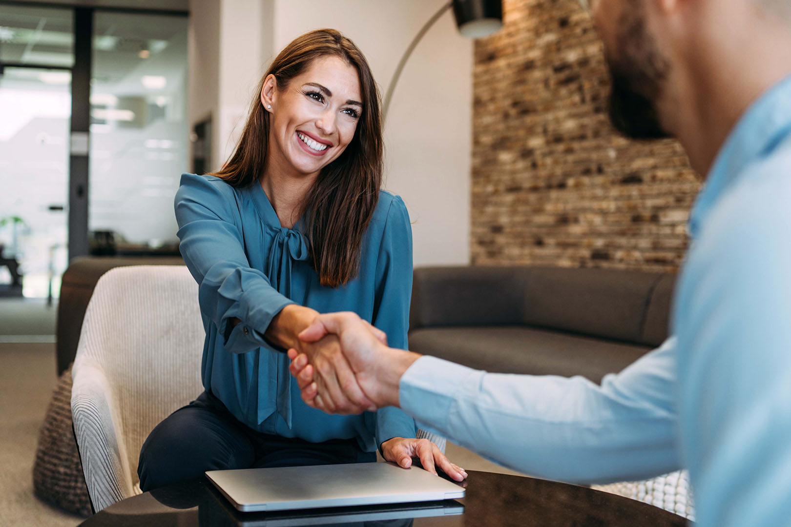 A woman shaking hands with a man at an office meeting
